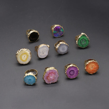 Collection of colorful rings with gold bands on a gray background