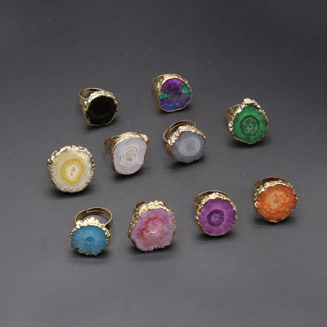 Collection of colorful rings with gold bands on a gray background