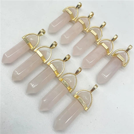 Set of rose quartz crystal pendants with gold accents on a white background
