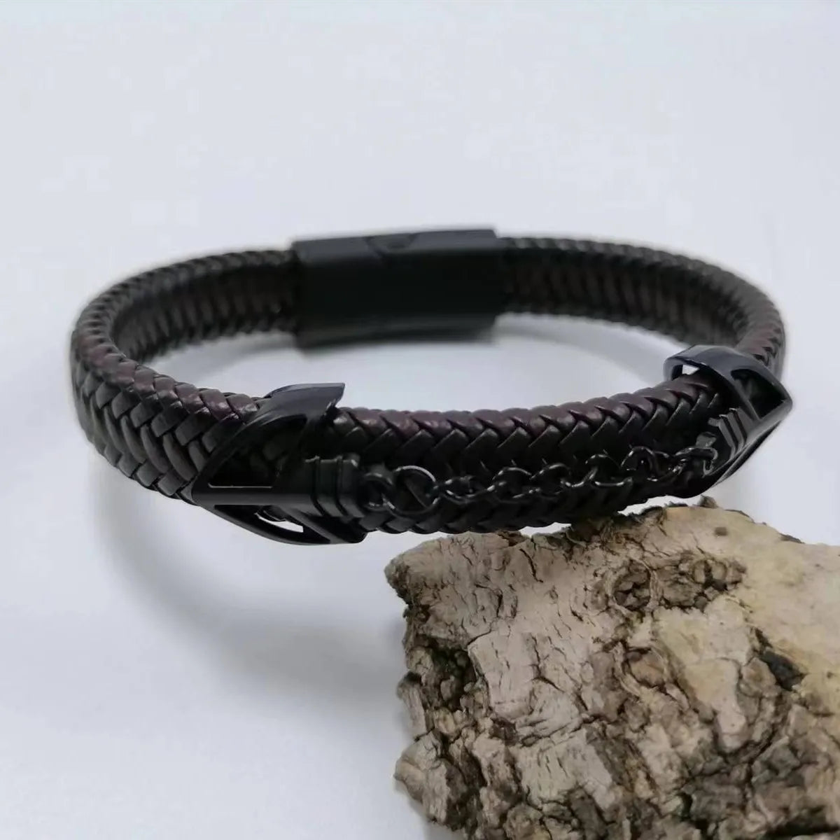 Black braided leather bracelet with a clasp on a light gray background