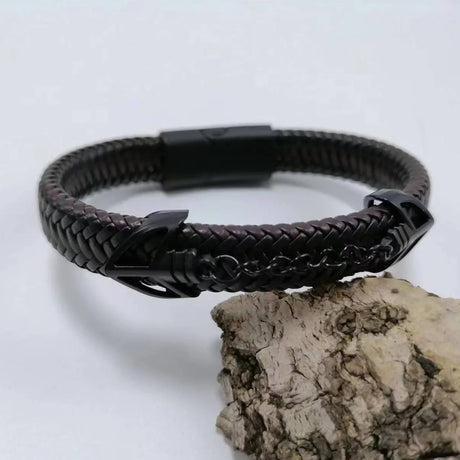Black braided leather bracelet with a clasp on a light gray background