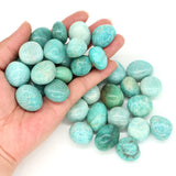 Turquoise stones held in a hand with a white background