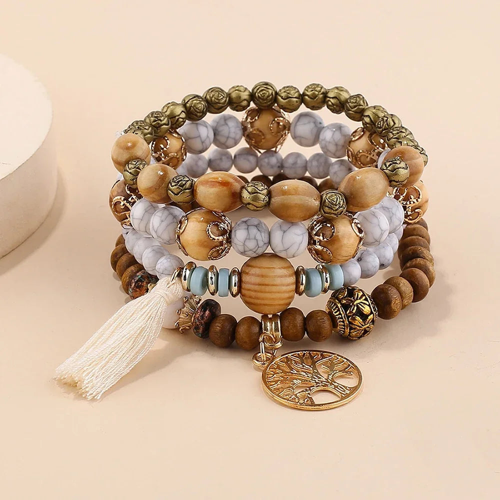 Set of beaded bracelets with a tassel and tree of life charm on a beige background