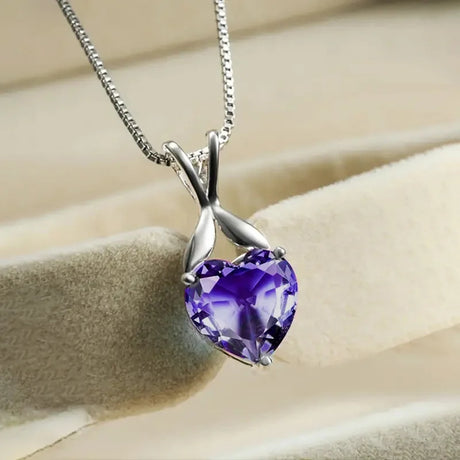 Purple heart-shaped gemstone necklace on a beige fabric background