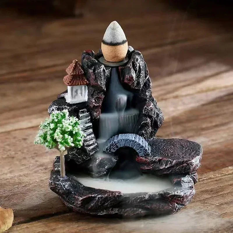 Decorative incense burner with a mountain and temple design on a wooden surface