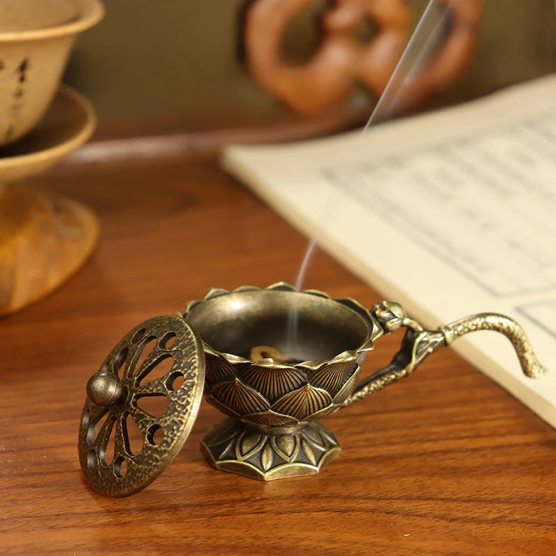Bronze incense burner with smoke on a wooden surface next to an open book
