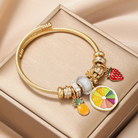 Gold bracelet with colorful charm on a beige surface