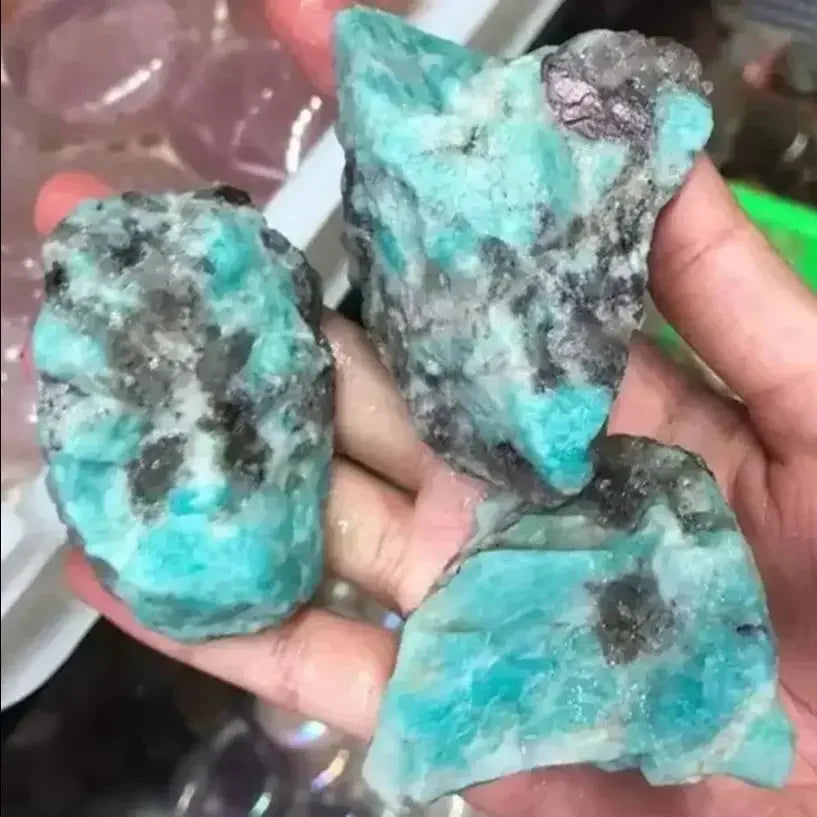 Raw turquoise stones held in a hand with a blurred background
