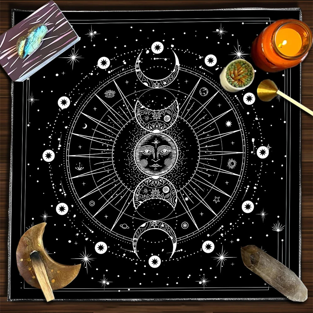 Black and white astrological design on a table with tarot cards, candle, and other items.
