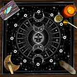 Black and white astrological design on a table with tarot cards, candle, and other items.