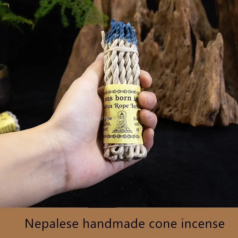 Hand holding Nepalese handmade cone incense with a natural background