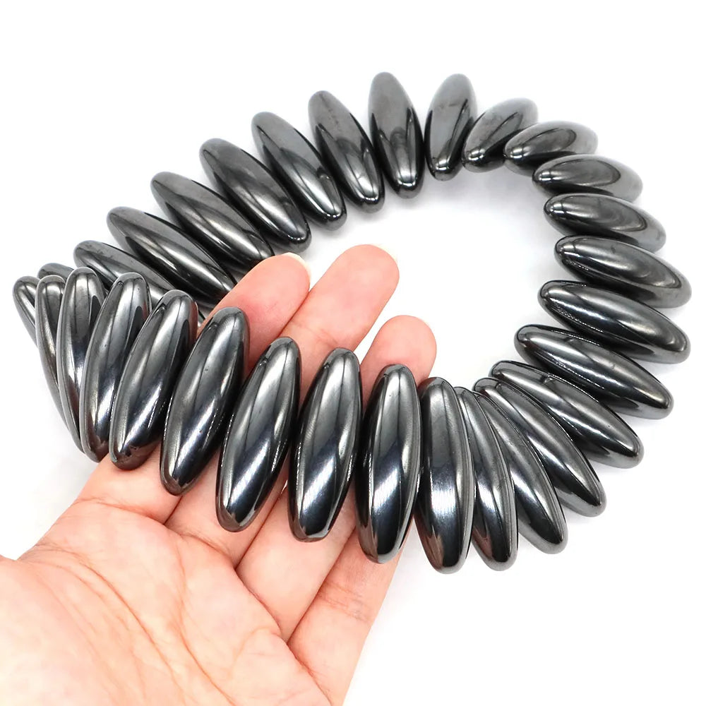 Coiled black hair tie held in a hand against a white background