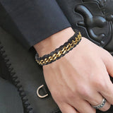 Hand wearing a black and gold chain bracelet on a dark background