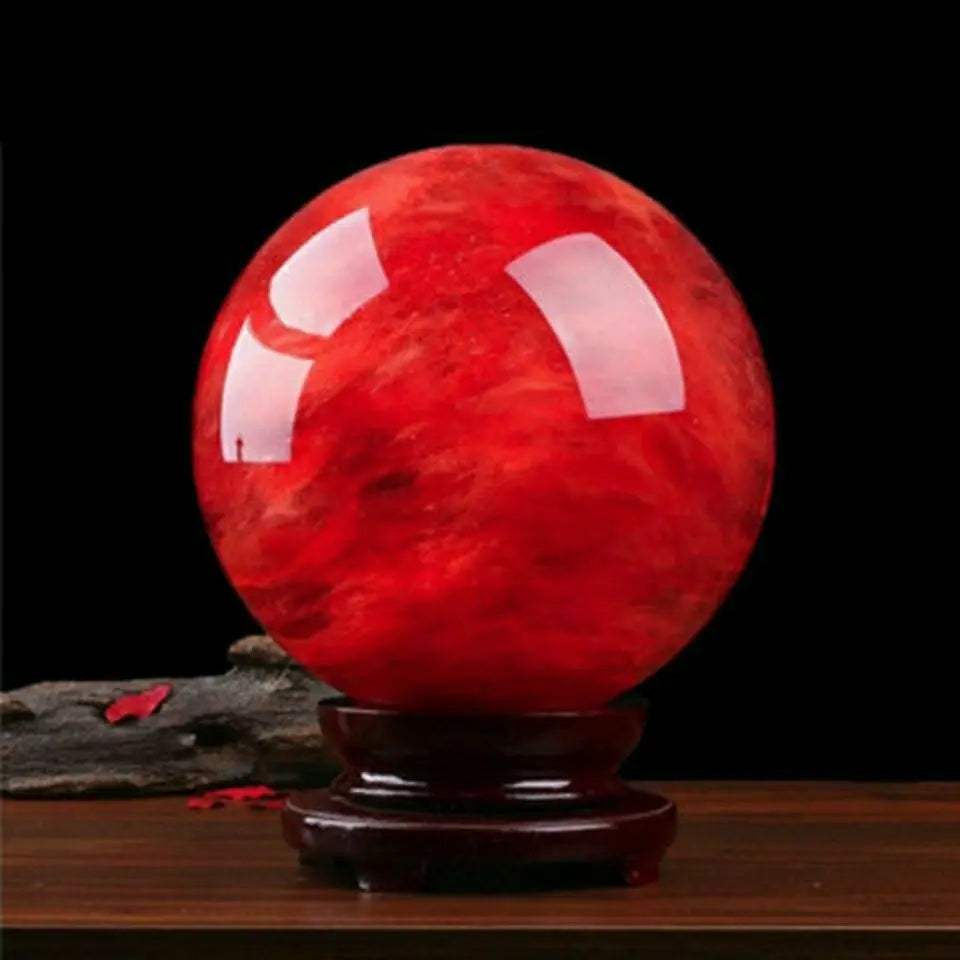 Red crystal ball on a wooden stand with a black background