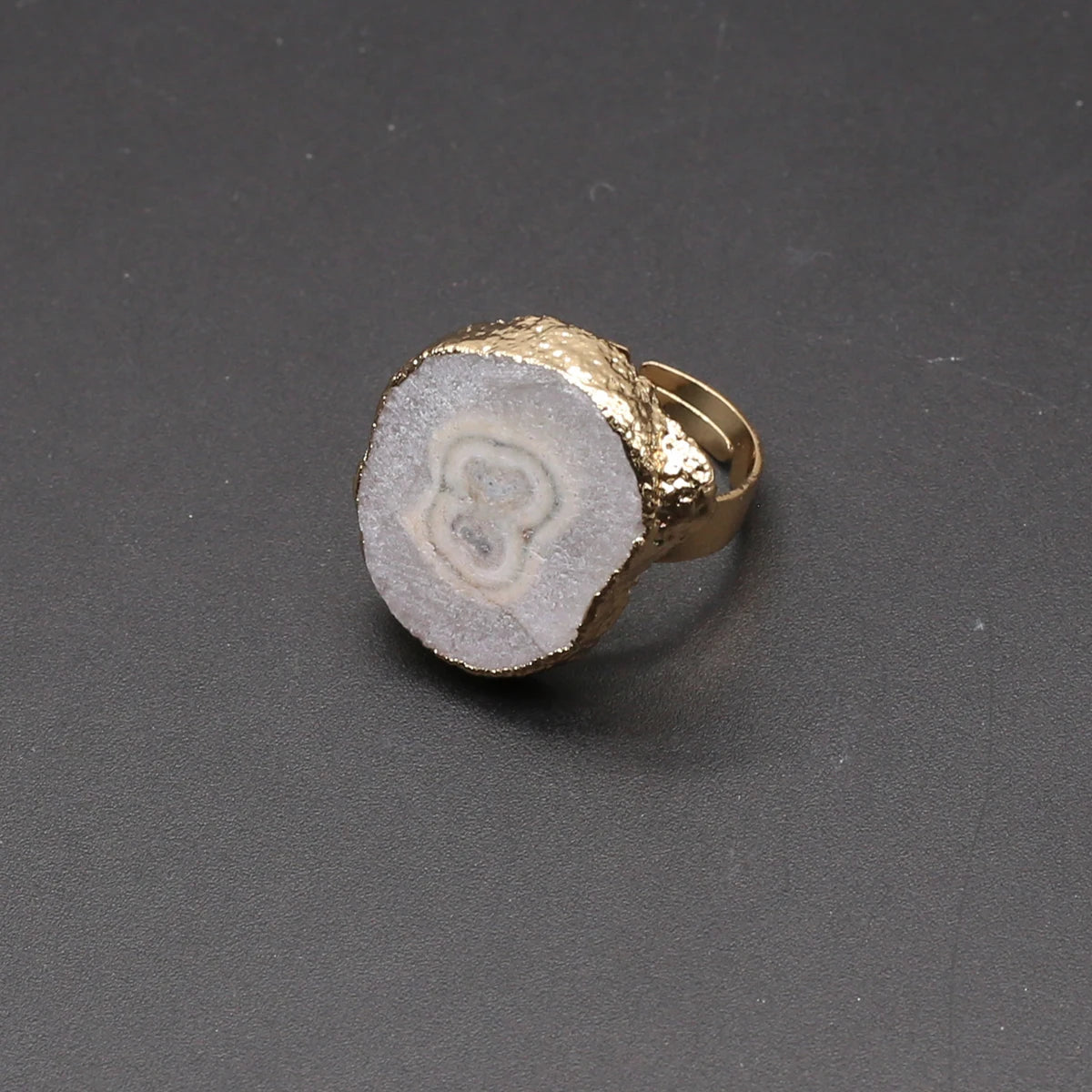 Ring with gold band and textured stone-like center on a dark gray background
