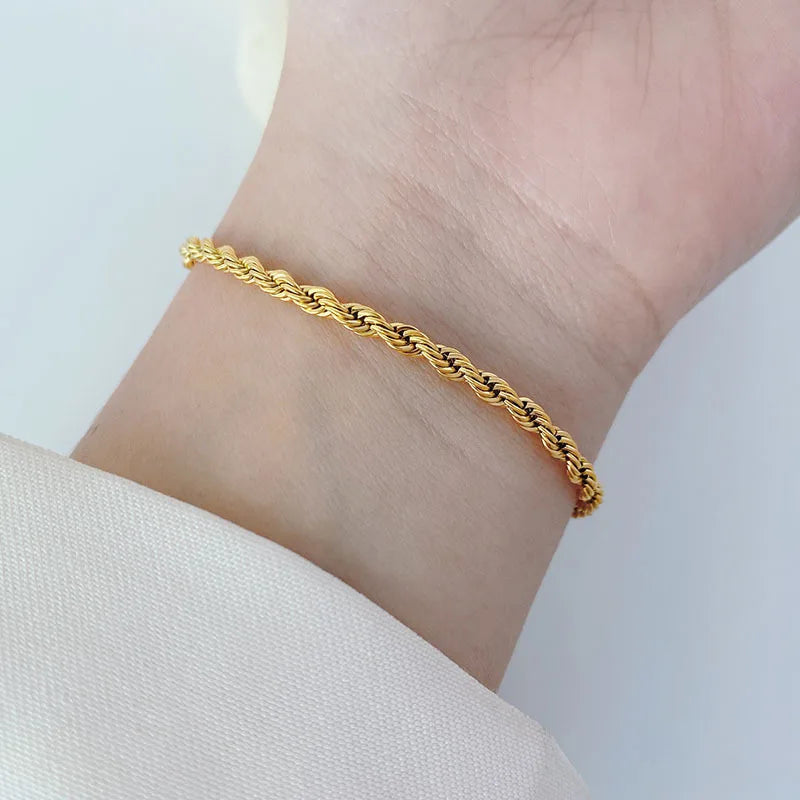 Gold bracelet on a wrist against a light background