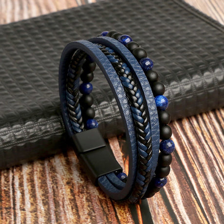 Blue and black braided leather bracelet with beads on a textured surface