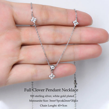 Silver necklace with clover pendants held in a hand against a white background