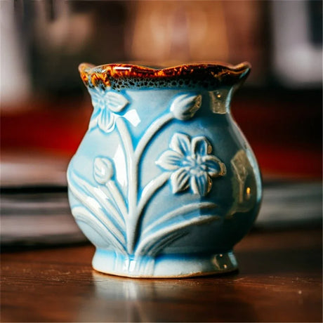 Blue ceramic vase with floral designs on a wooden surface