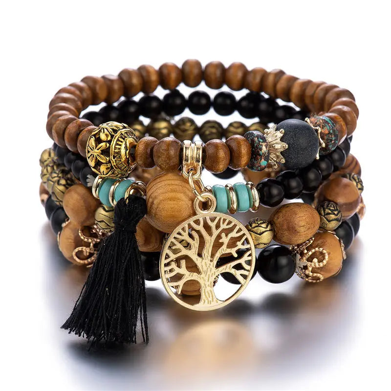 Stack of beaded bracelets with tree of life charm on a white background