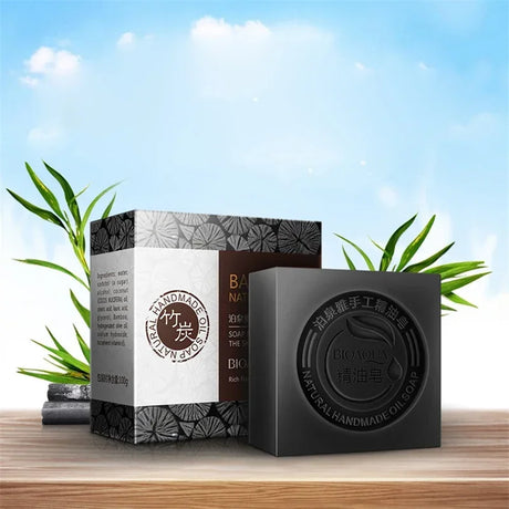 Black soap bar and packaging on a wooden surface with a natural background