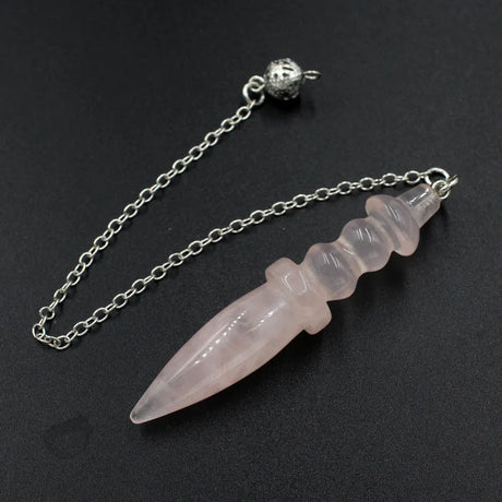 Crystal dagger pendant on a chain against a black background