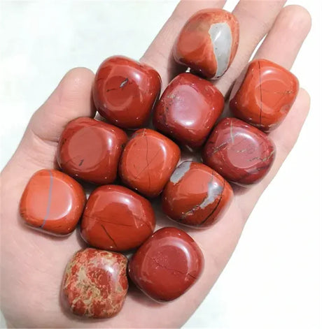 Hand holding red marbled stones against a white background
