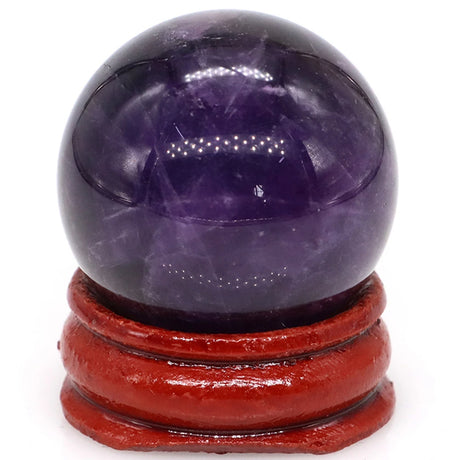 Amethyst crystal ball on a red wooden stand against a white background