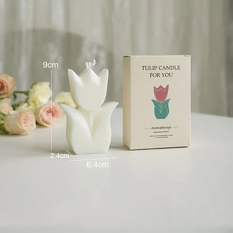 Tulip-shaped candle with packaging and floral arrangement on a light surface