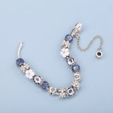 Beaded bracelet with floral and crystal designs on a light blue background