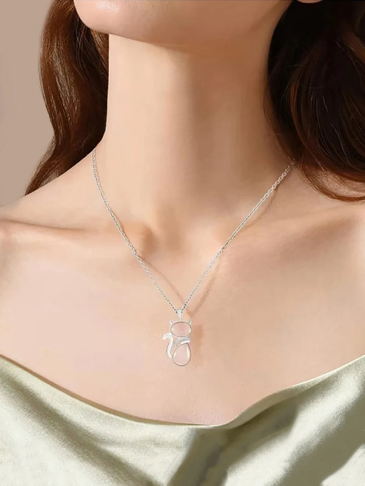 Silver necklace with a pendant worn by a person against a neutral background
