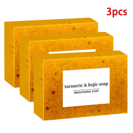 Three bars of turmeric and kojic soap in yellow packaging with a white label on a white background.