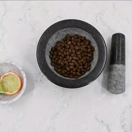 Mortar and pestle with dried herbs on a marble surface