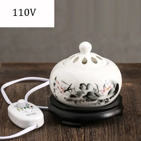 White ceramic oil burner with floral design on a wooden surface, labeled 110V.