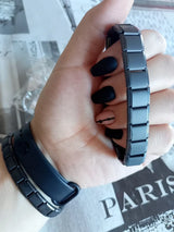 Hand wearing a black metal bracelet on a newspaper background