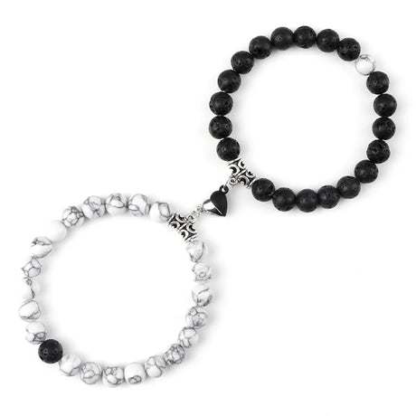 Two bracelets, one black beaded and one with white pattern and black beads, on a white background.