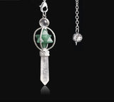 Jewelry pendant with green stone and silver chain on a black background
