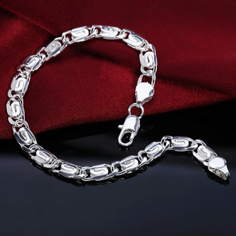 Silver chain bracelet on a dark surface with a red fabric background