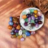 Assorted colorful gemstones on a white plate with a wooden background