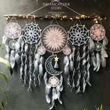 Set of dreamcatchers with feathers hanging against a dark background.