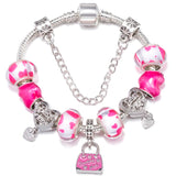 Bracelet with pink and white heart-themed beads and silver charms on a white background