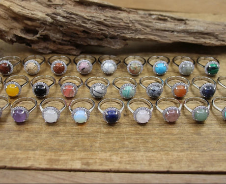 Assorted gemstone rings on a wooden surface with a rustic background