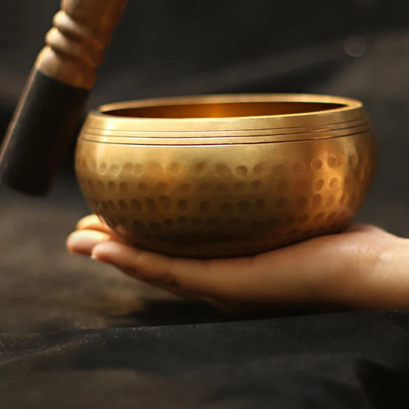 Person holding a bronze singing bowl with a dark background