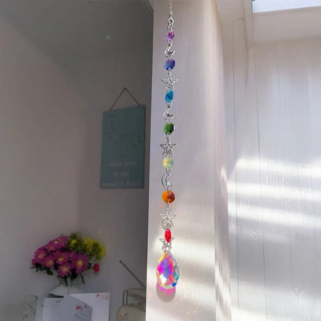 Colorful crystal hanging decoration in a room with flowers and a poster on the wall.