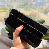 Black jewelry organizer held by a hand with red nail polish, outdoors.