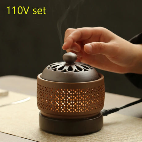 Ceramic incense burner with a hand placing a stick inside, on a neutral background.