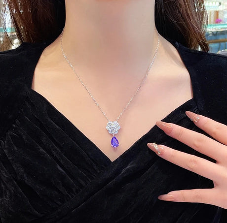 Person wearing a necklace with a purple pendant, brand 'CUMEE' visible