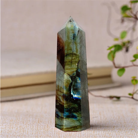 Multicolored crystal tower on a textured surface with a blurred plant in the background