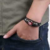Bracelet with a red and silver charm on a wrist, wearing a green shirt and blue jeans.