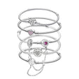Stack of silver bracelets with heart-shaped charms on a white background